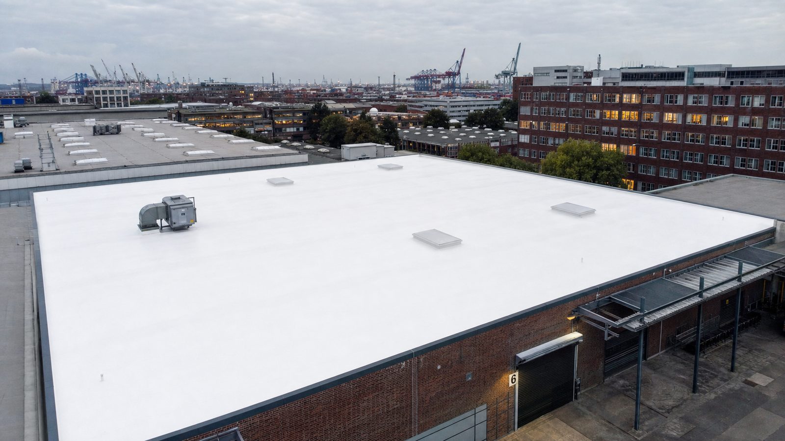 Industrielles Flachdach eines Logistikgebäudes in Hamburg-Hammerbrook mit nahtloser Flüssigabdichtung und Blick auf die Hafenkräne